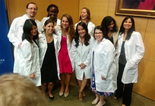Graduate students pose together happily after receiving their white coats.